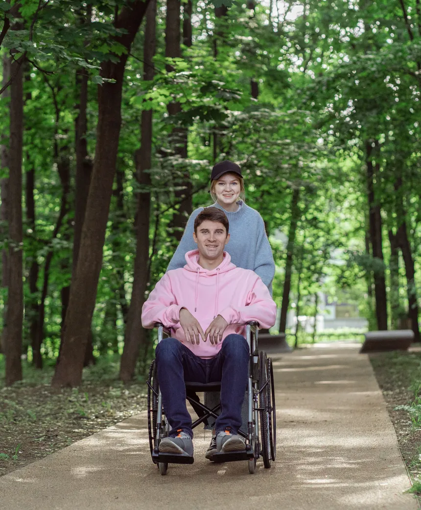 A support worker and a participant walking together through a park on the Peninsula