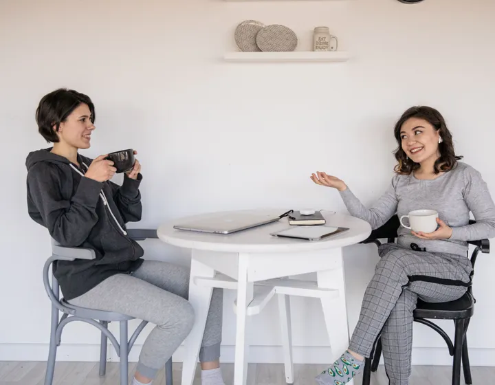 Two people talking options through over coffee, with a laptop and notebook on the table
